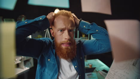 retrato de un hombre pelirrojo estresado eligiendo la decisión correcta en una oficina hipster.