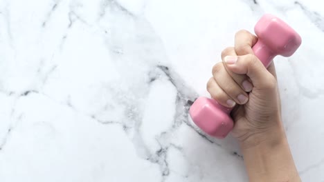 pink dumbbell in hand on marble surface