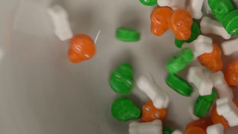 extreme close up of bones and skulls shaped candy falling on a plate