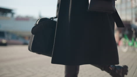 close-up of leather boot and flowing coat detail, capturing movement and elegance with sheer tights on an urban street, background includes blurred motion of car and modern architecture