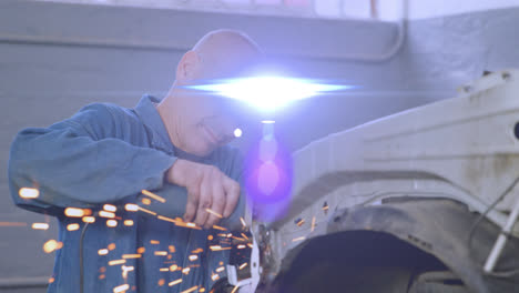 animation of blue light moving over male caucasian mechanic using grinding tool on car in garage