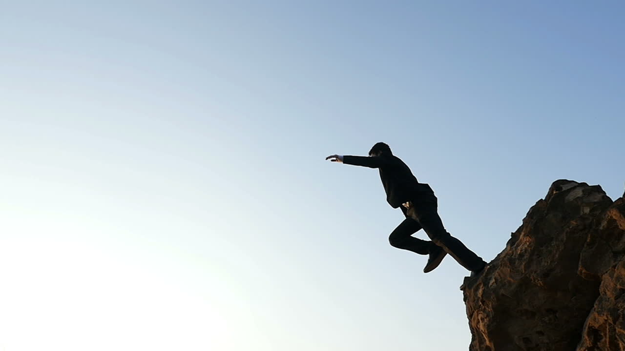 Businessman Jumping from Cliff