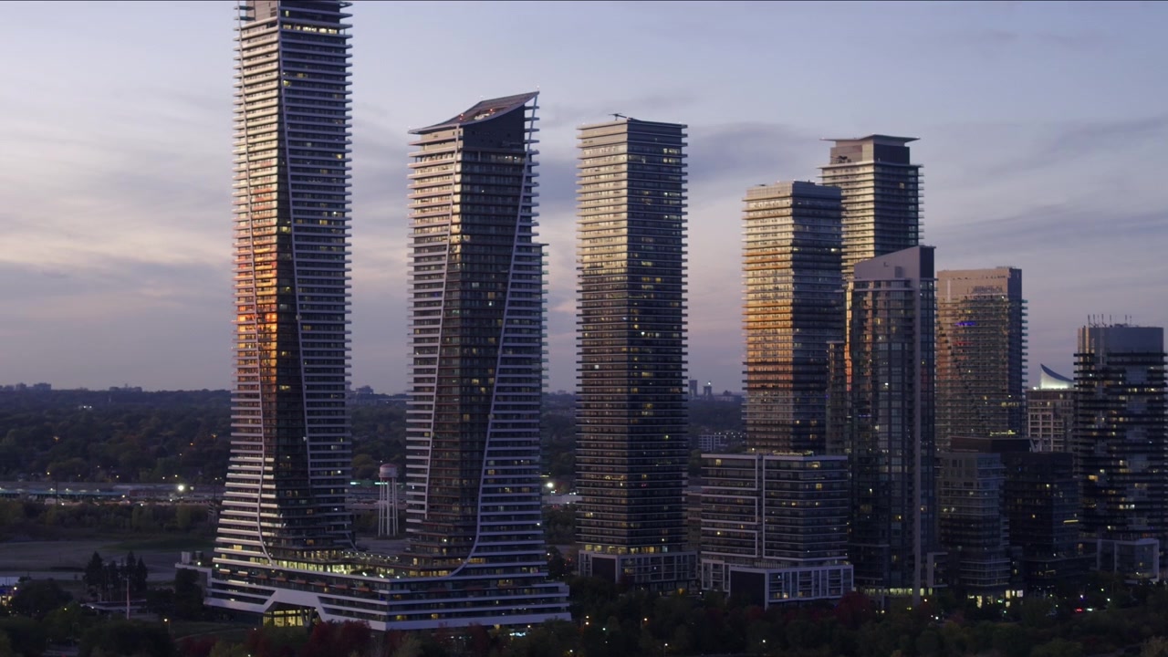 Grattacieli di vetro lungo il lungomare di Etobicoke riflettono la calda luce dorata di un tramonto. Le torri residenziali a molti piani si ergono alte contro un cielo crepuscolare