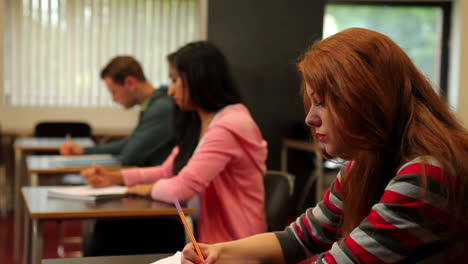 estudiantes atentos sentados en un aula y tomando notas