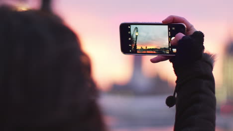 woman takes photo of big ben on mobile phone at sunset