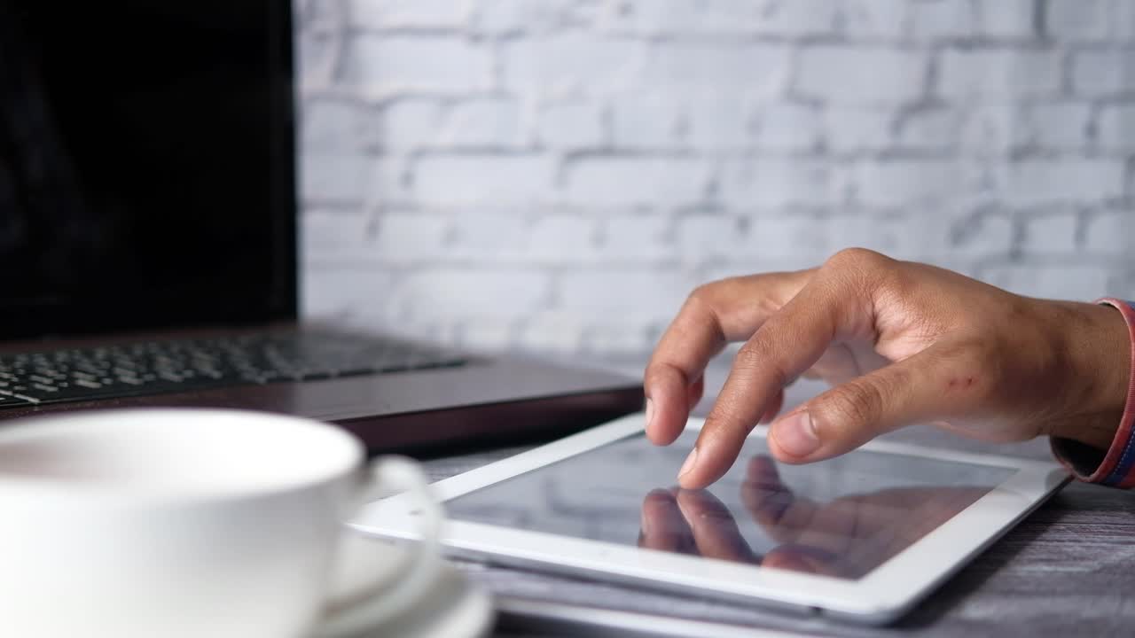 persona que utiliza una tableta y una computadora portátil en un espacio de trabajo