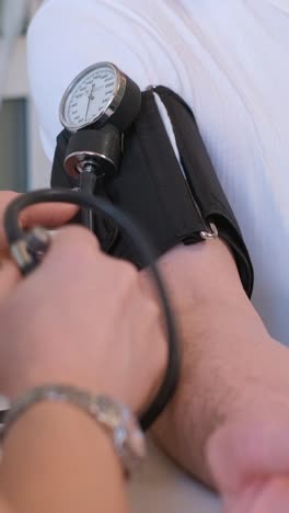 zoom in shot of young male therapist in white coat measuring blood pressure of senior patient in ward of clinic