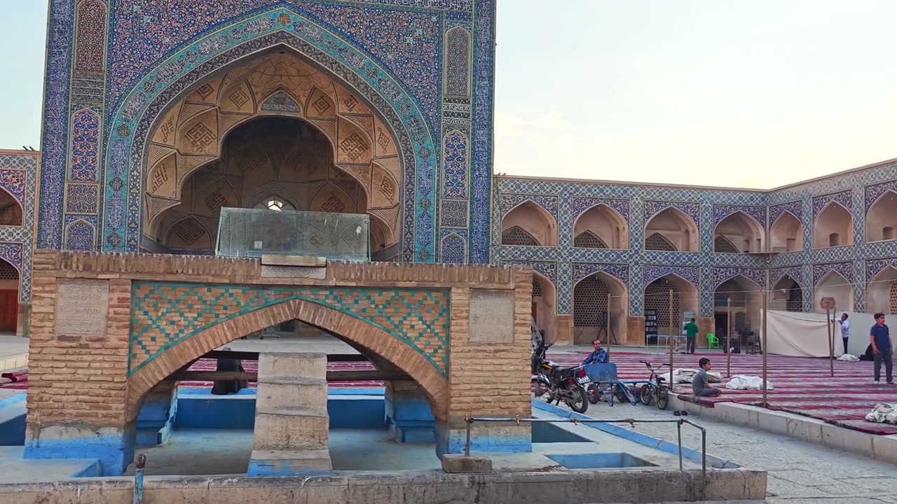 Menschen entspannen im Innenhof einer historischen persischen Moschee