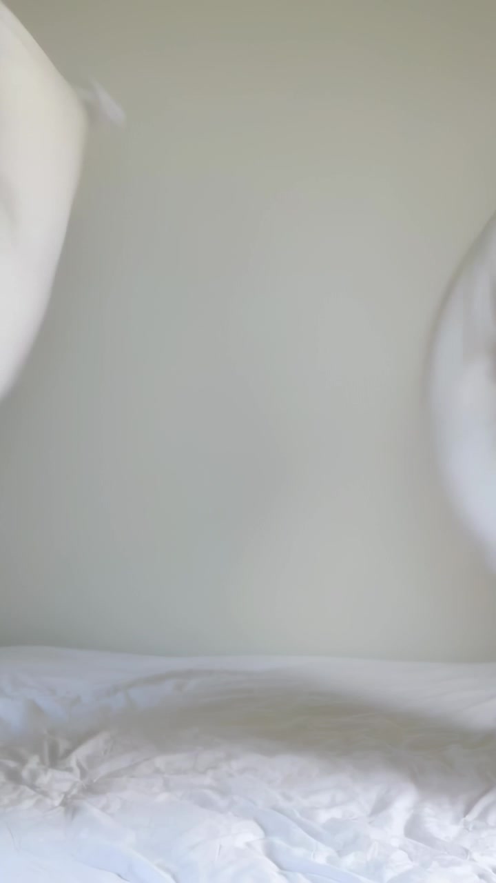 Video verticale: Due cuscini si muovono attraversando il letto in camera da letto, arrivando dai lati e sistemandosi.