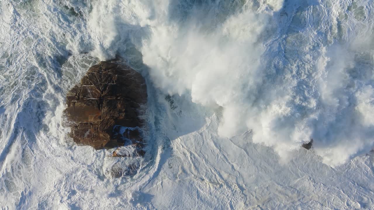 Kraftfulde hvide havbølger, der slår i slowmotion mod den stenede kystlinje ved Arteixo, Spanien. Luftfoto i fugleperspektiv