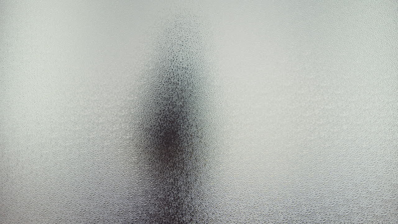 A female silhouette behind the frosted window dances slowly
