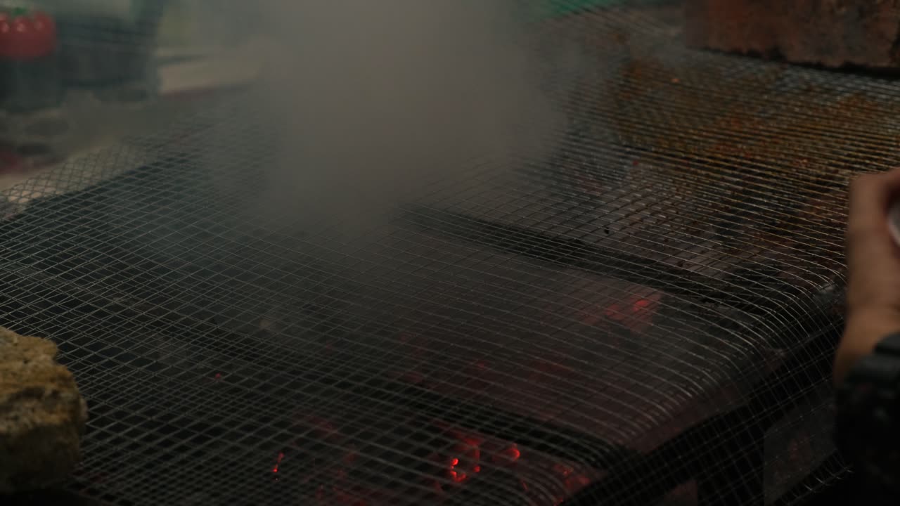 부추를 사용하여 바비큐 그릴에서 식사를 준비하는 손의 근접 촬영 보기