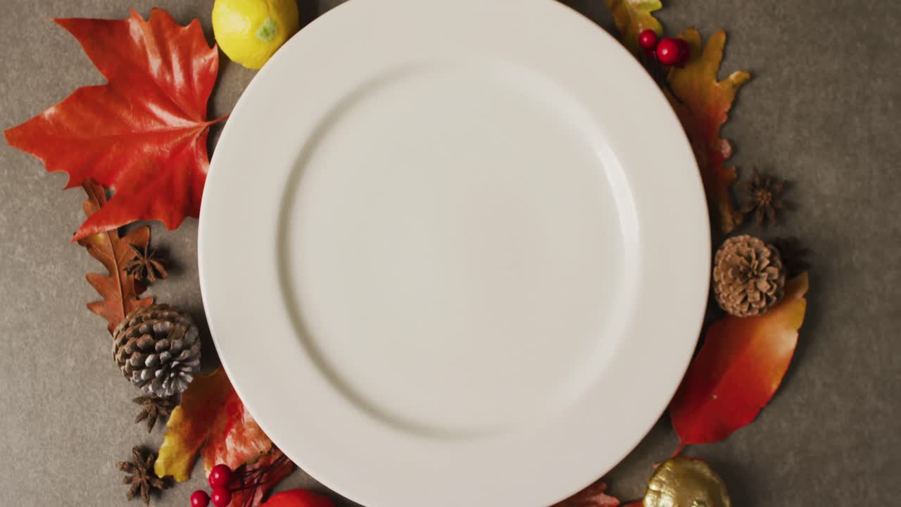 video de un plato con hojas de otoño y decoración sobre una superficie gris