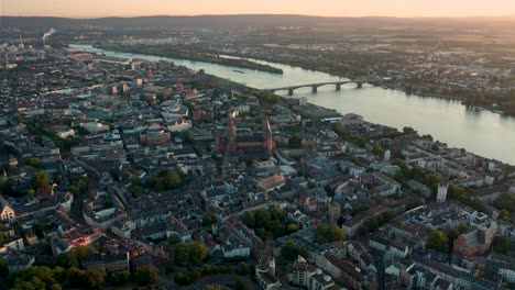 Stadt-Mainz-Durch-Eine-Drohne-Im-Frühen-Morgenlicht,-Die-Den-Dom-Und-Die-Innenstadt-Mit-Dem-Rhein-Im-Hintergrund-Umkreist