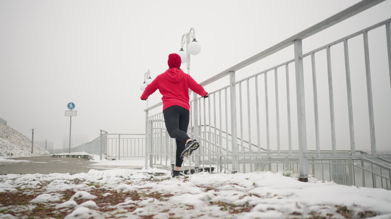 겨울 동안 야외에서 운동하는 운동선수, 다리를 앞뒤로 는 동안 뒷받침을 위해 철의 레일링을 들고. 안개 분위기, 조명 기둥, 계단, 배경에 눈 인 땅