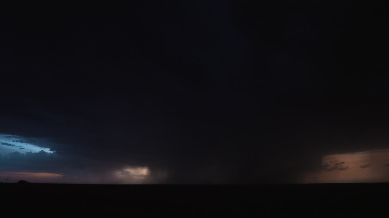Nighttime storm clouds are filled with light as a bolt of lightning strikes