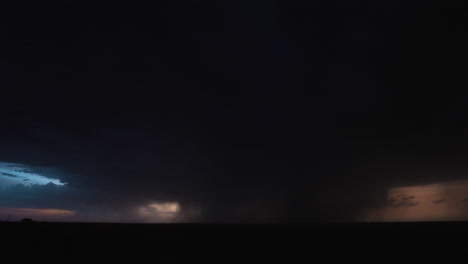 nighttime storm clouds are filled with light as a bolt of lightning strikes