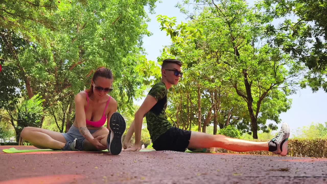 una pareja estirándose en el parque.