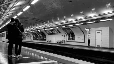 underground in paris in a black and white video while the metro arrives at the subway station