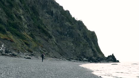 a man walks alone on a beach near a cliff