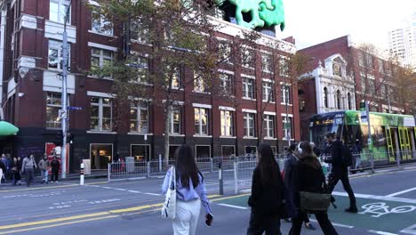 people crossing street near tram and buildings