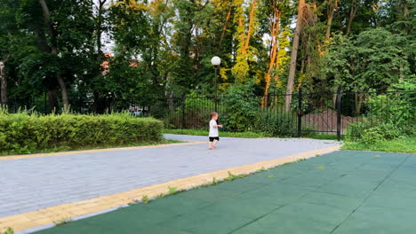 active barefoot toddler boy running outdoors. kid wearing t-shirt and shorts running away in the park.