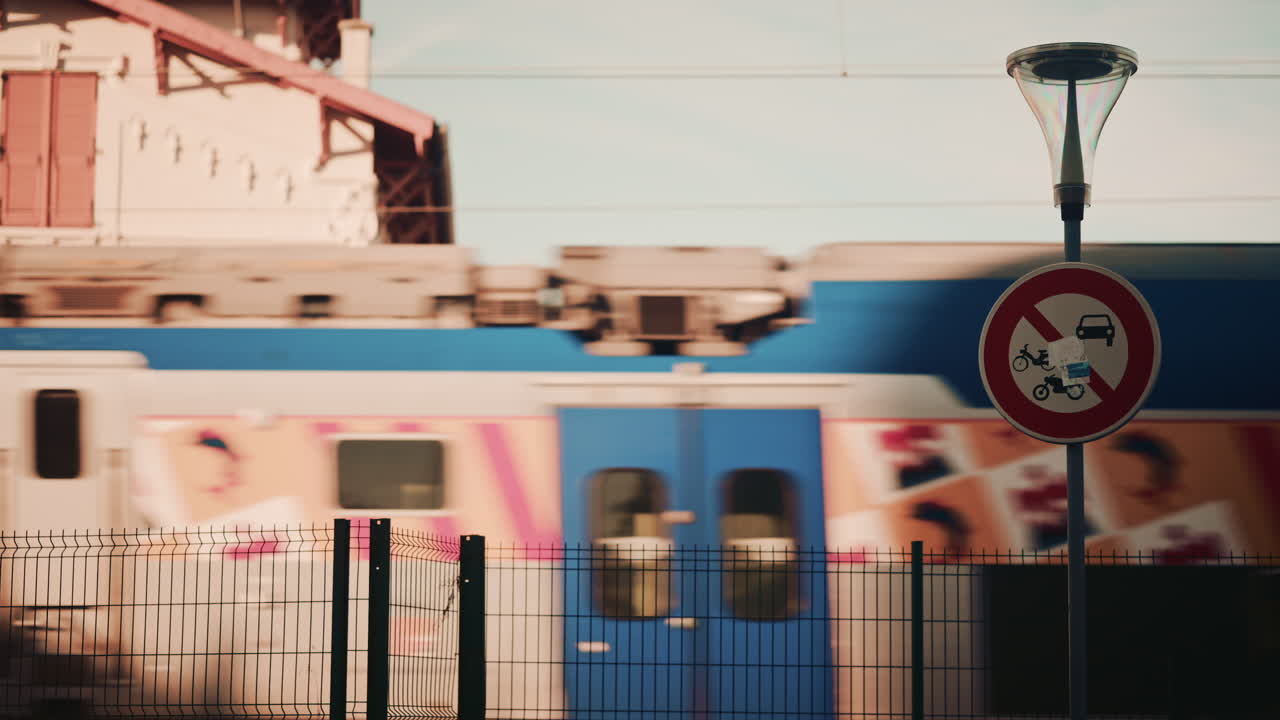 Fast moving train passing behind a road sign during daylight, captured with motion blur