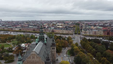 Vista-Aérea-Del-Museo-Nórdico-En-Estocolmo,-Suecia,-Se-Puede-Ver-La-Isla-Djurgarden,-Al-Fondo-La-Ciudad-Con-Sus-Canales-Y-Barcos