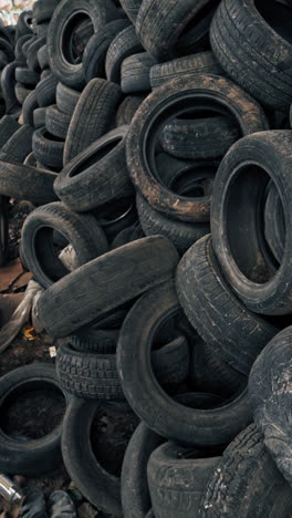 lot of old tires from cars. second hand tyres stacked up at old dump vertical video