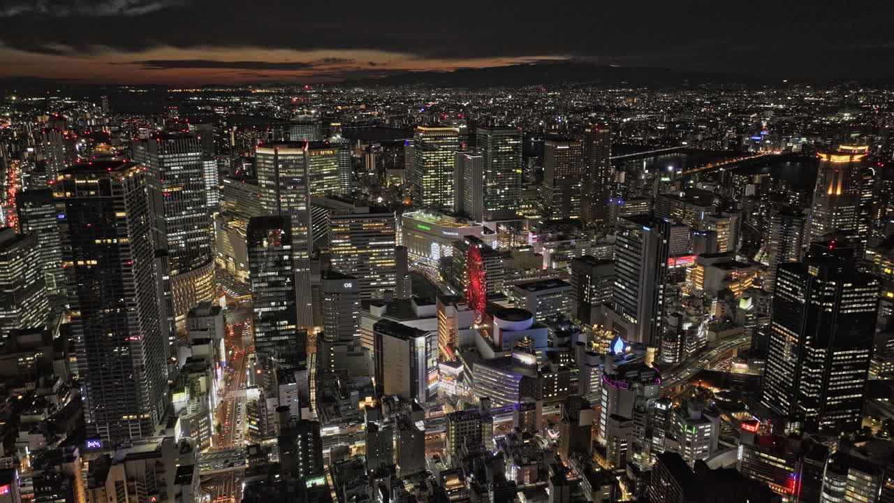 Osaka Japan Aerial v93 tracking flyover capturing vibrant night cityscape of Kita Ward, with towering skyscrapers dominating the districts in downtown area - Shot with Mavic 3 Pro Cine - Oct 9th 2023