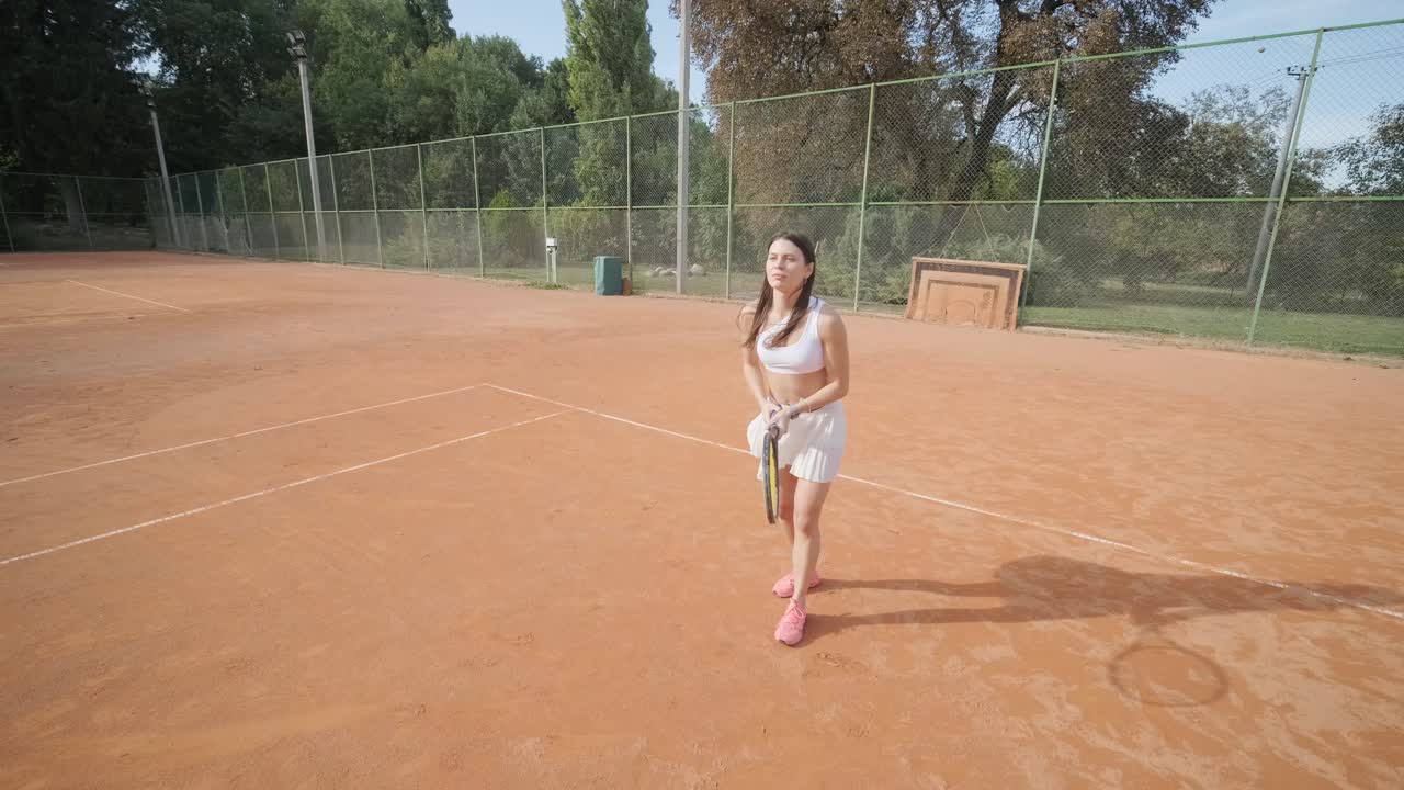 코치와 함께 야외 코트에서 테니스를 연습하는 젊은 여성. 코치는 선수가 그녀의 기술에 대해 일하면서, 운동 훈련 세션에서 그녀의 스트로크를 완성하는 동안 지침을 제공합니다.