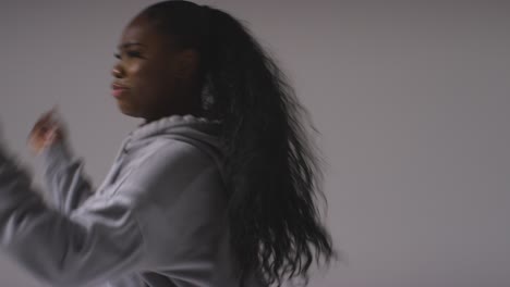 Studio-Portrait-Shot-Of-Young-Woman-Wearing-Hoodie-Dancing-With-Low-Key-Lighting-Against-Grey-Background-13