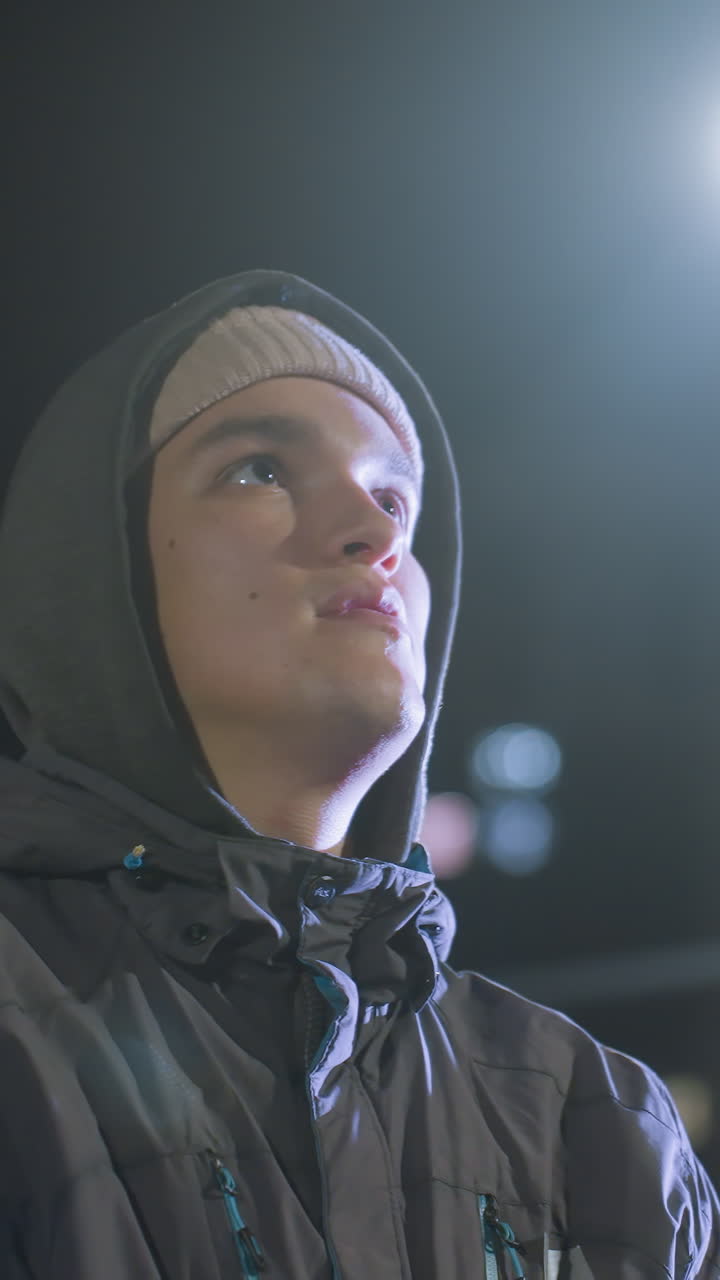 primer plano de un futbolista con guantes lanzando una pelota de fútbol al aire y atrapándola con un fondo urbano borroso, las luces de la noche crean un efecto bokeh