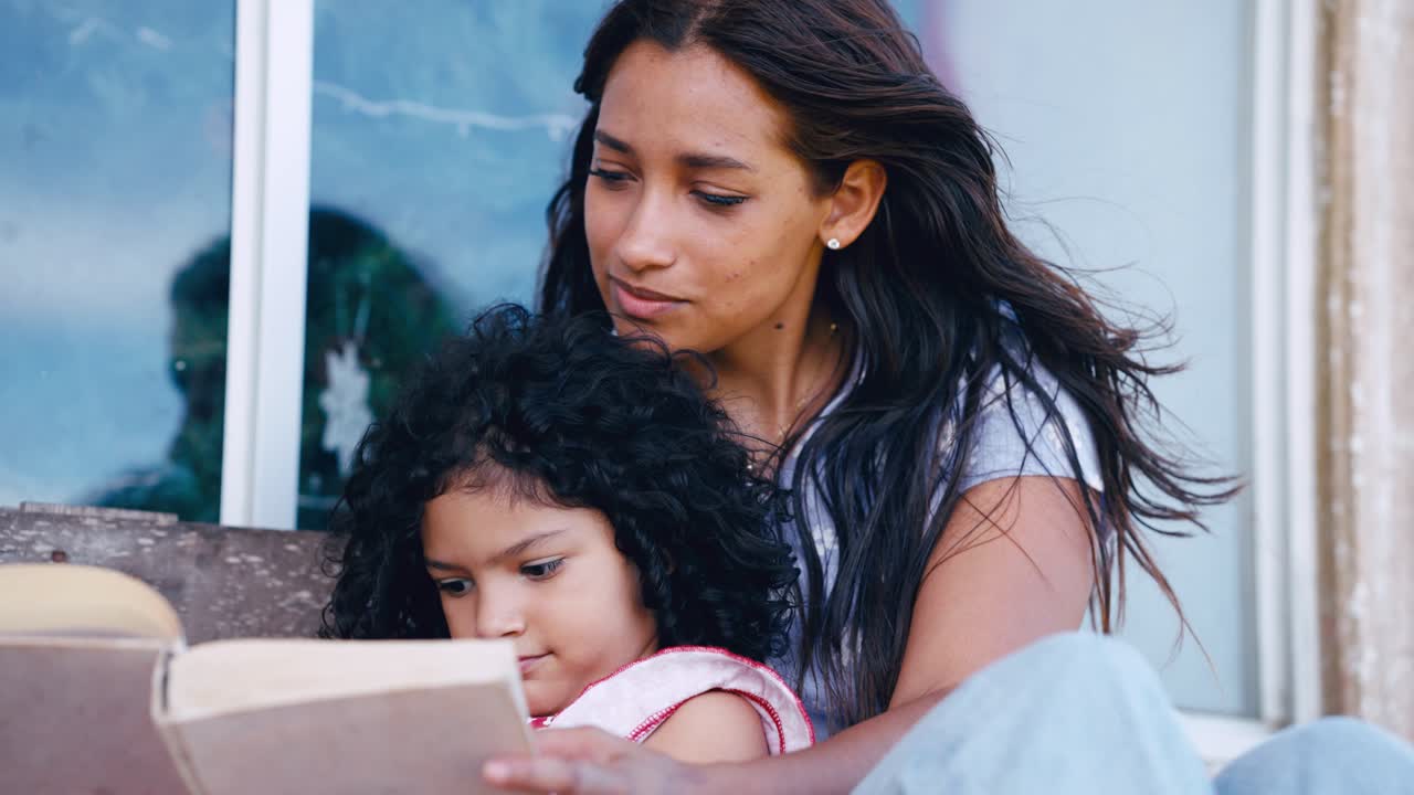 Young Mother and Daughter Reading a Book Together Outdoors