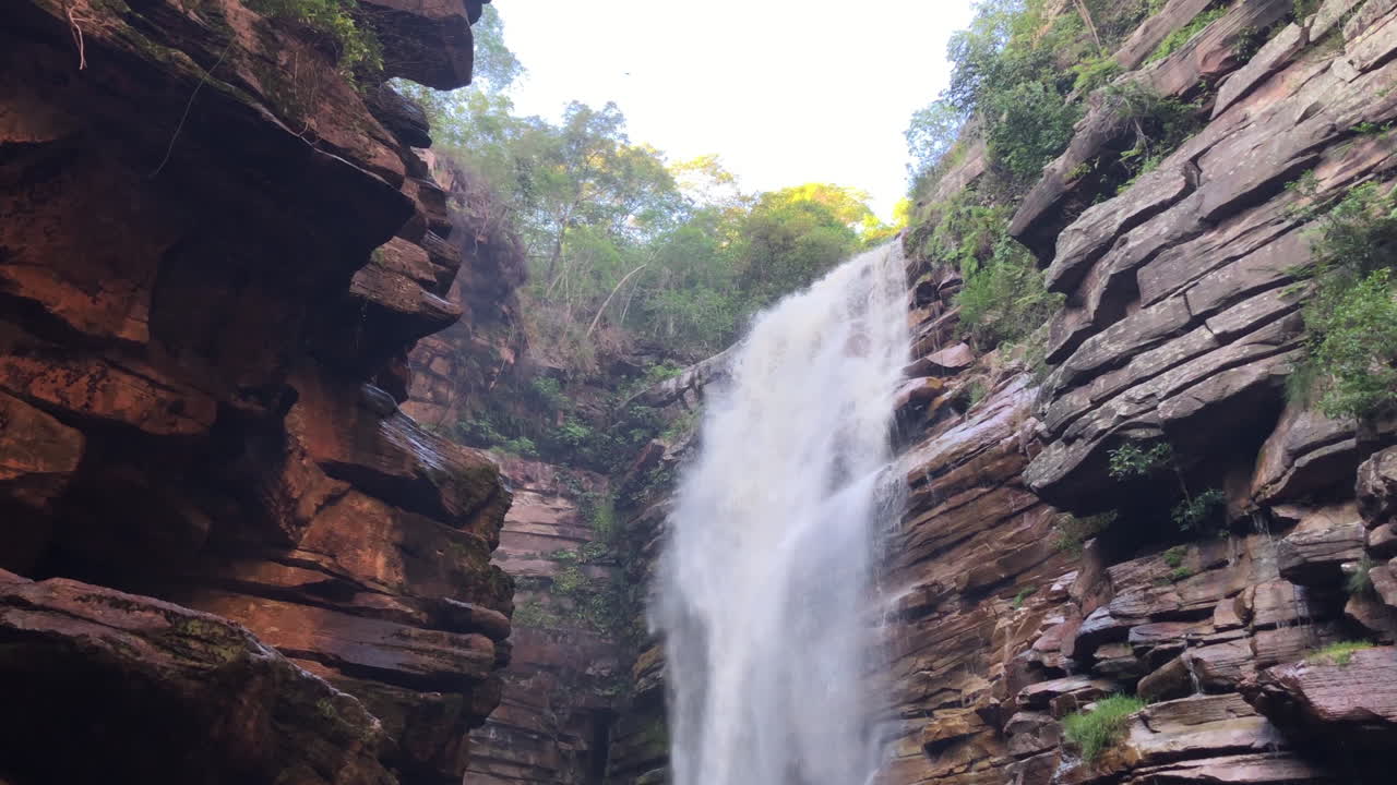 A beautiful waterfall. We can see two small birds flying in front of the waterfall in this video