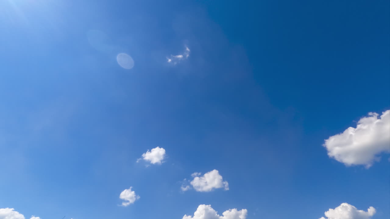 Tiny light soft clouds appearing in the bright blue sky. Sunrays going through the clouds. Timelapse.