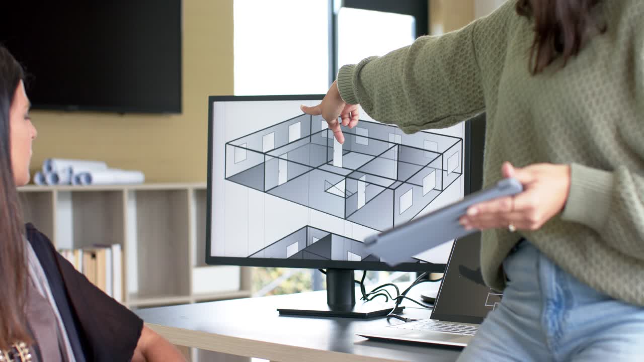 Diverse female coworkers using tablet while pointing floor plan on monitor at office, copy space