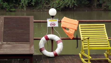 a warning sign advising people of no swimming in the fast flowing waters of the khwae river, safety equipment is provided in the case of an emergency in kanchanaburi, thailand