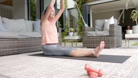 mature caucasian woman stretching on yoga mat outdoors