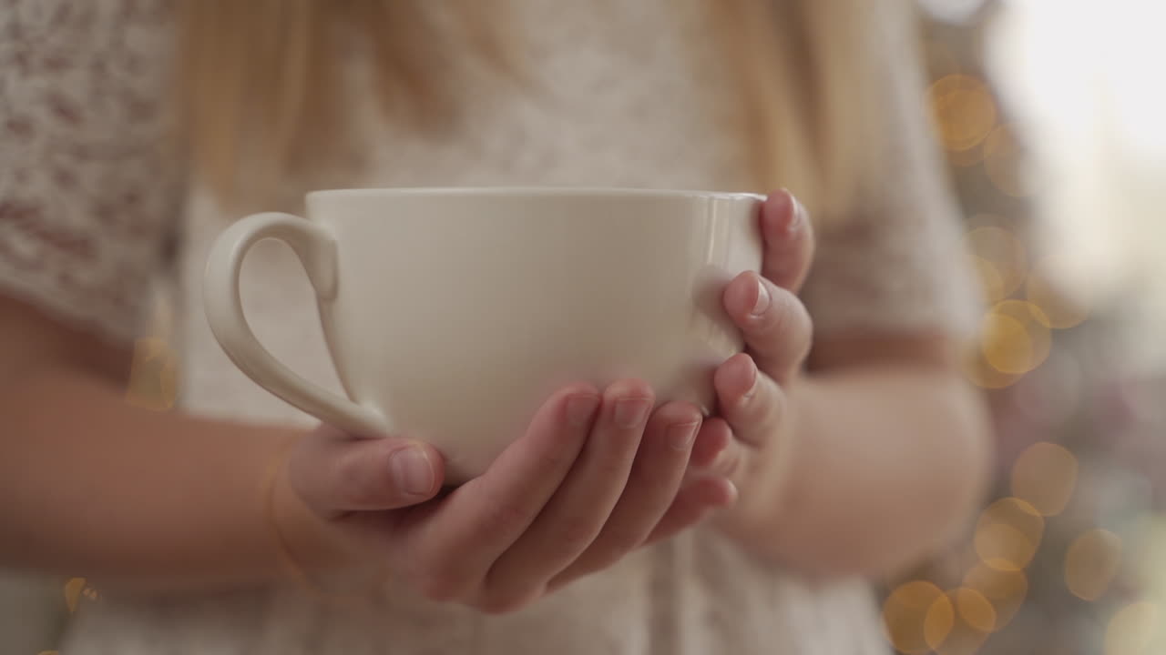 Girl's hands holding big cup. Close-up.