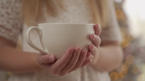 manos de niña sosteniendo una taza grande. de cerca.