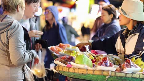 foreigners buying fruit from a street vendor