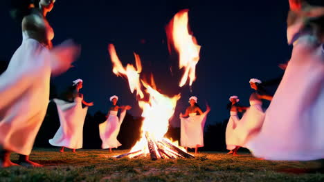 women dancing around a campfire at night