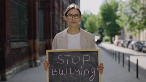 woman holding sign saying 'stop bullying'