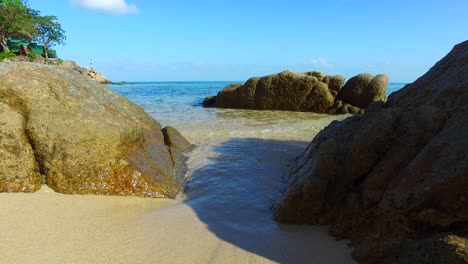 Beautiful-cliffs-on-sandy-shore-of-tropical-island-washed-by-calm-clear-water-of-sea-on-a-bright-sky-background-in-Vietnam