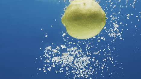 video de limón cayendo en el agua con espacio de copia en fondo azul
