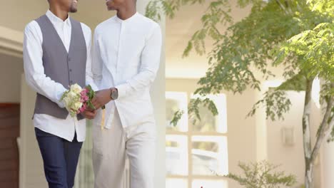 Midsection-of-african-american-gay-male-couple-holding-hands-and-flowers-at-wedding,-slow-motion