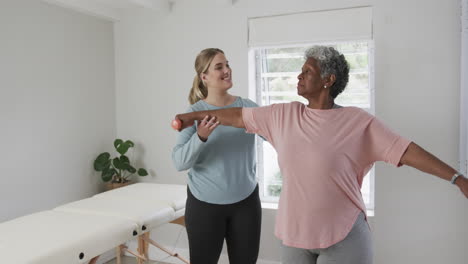 Caucasian-female-physiotherapist-with-senior-woman-exercising,-copy-space,-slow-motion