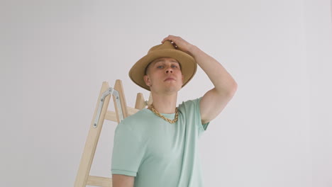 young man putting a hat on a ladder