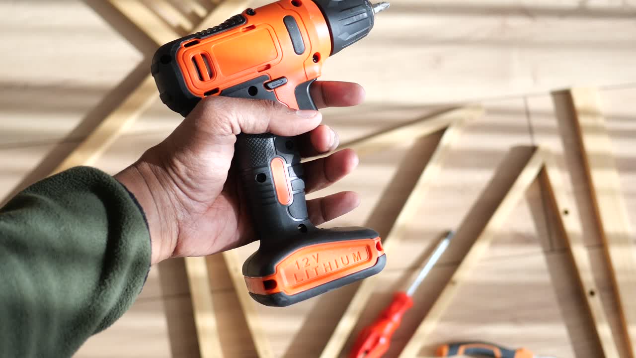 Person using a cordless drill to assemble wooden furniture